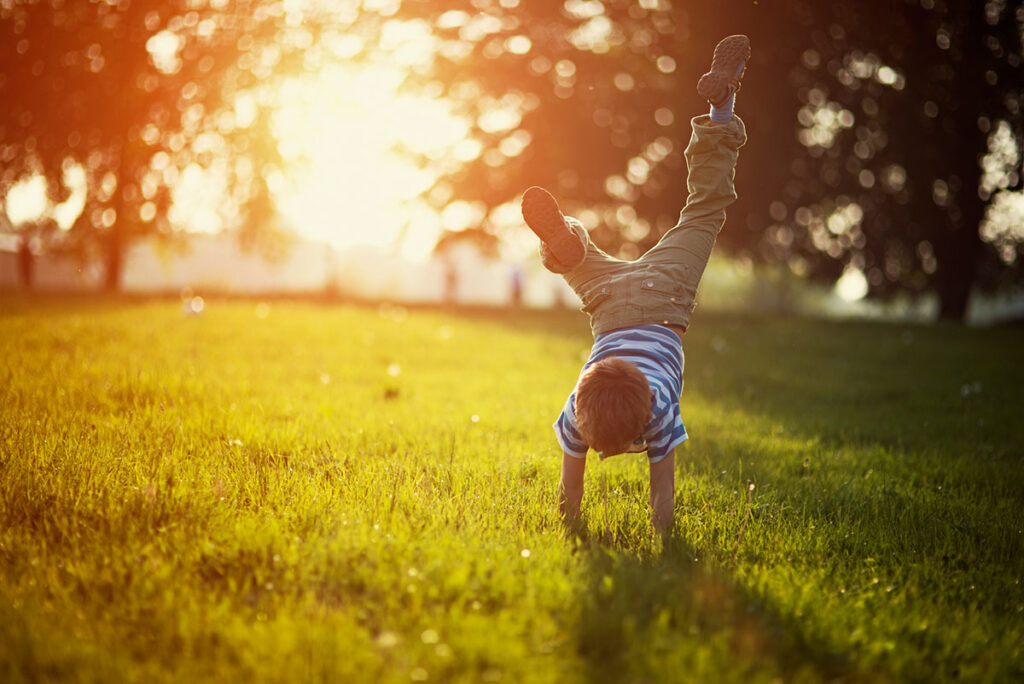 Ein kleiner Junge macht im Abendlicht einen Handstand